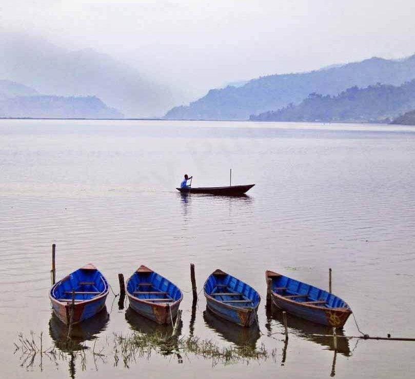 Travel in Nepal: A man in a boat sailing across Lake Fewa in Pokhara, Nepal