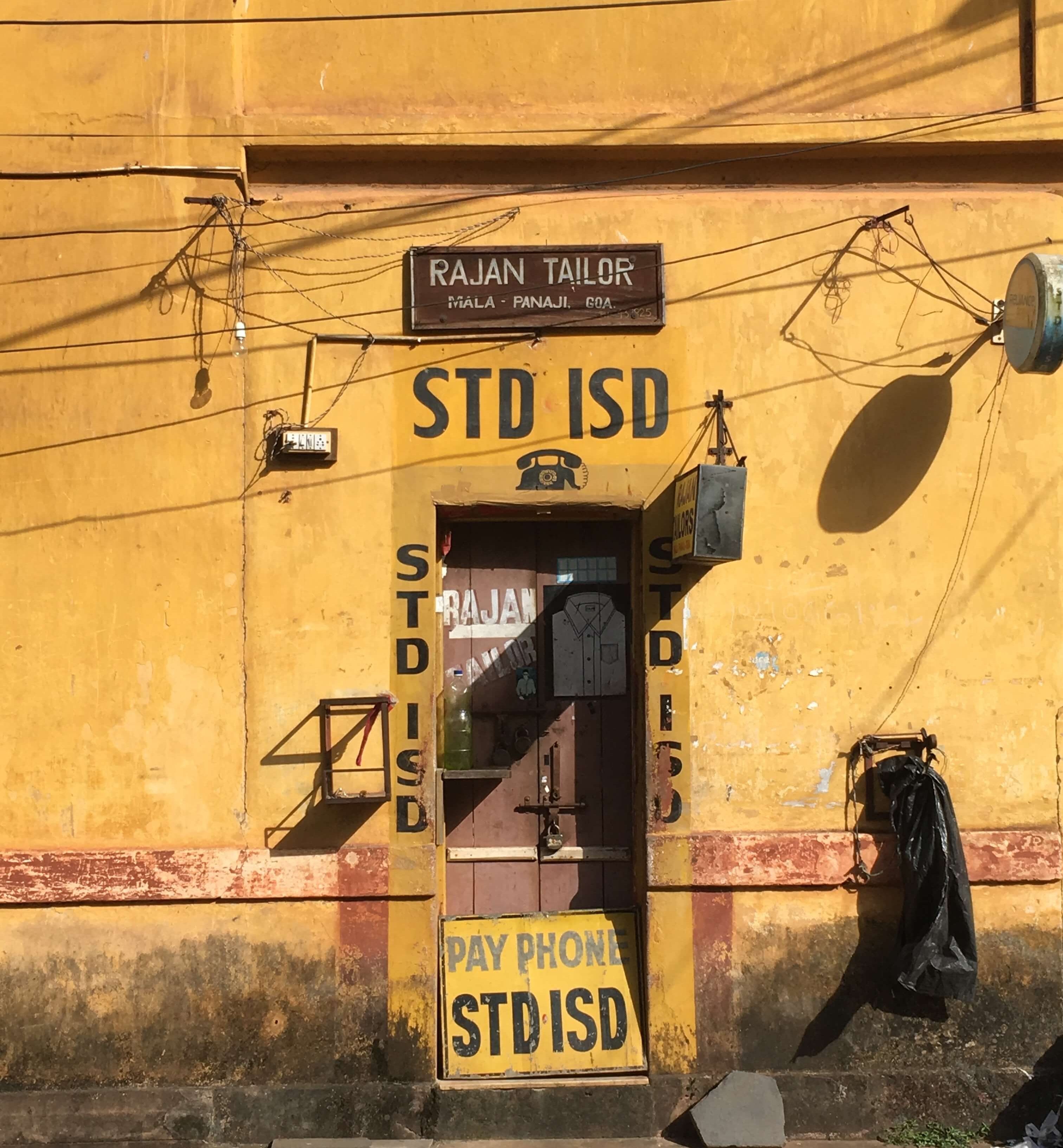 Tailor and pay phone in a yellow building in Panaji, Goa